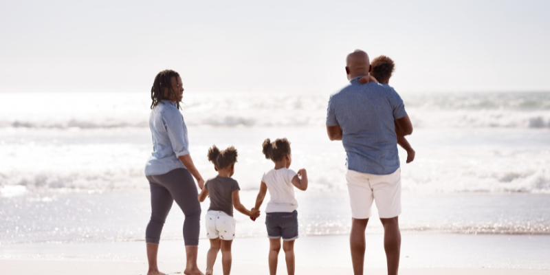 Family Friendly Environment African American family walking away from the camera on the beach.
