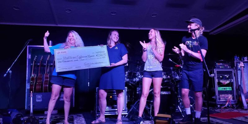 Seaside Vacations’ Lori Smith presents a check to Hatteras Island Meals at Thursday’s Koru Beach Klub concert Seaside Vacations’ Lori Smith presents a check to Hatteras Island Meals at Thursday’s Koru Beach Klub concert