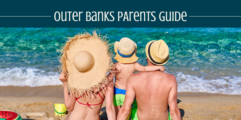 Outer Banks Parents Guide Mom, dad, and son sitting on the shore in front of the ocean.