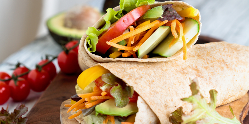Beach Snacks - Veggie Wraps Image of whole wheat tortilla filled with cucumbers, carrots, tomatoes, and lettuce.