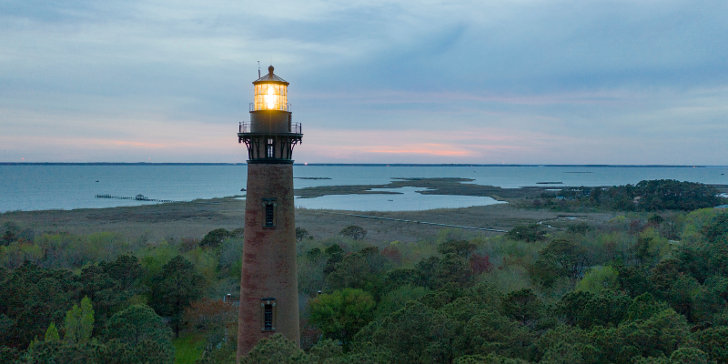 Currituck Beach Lighthouse Image of Currituck Beach Lighthouse with light glowing in front of marsh/sound.