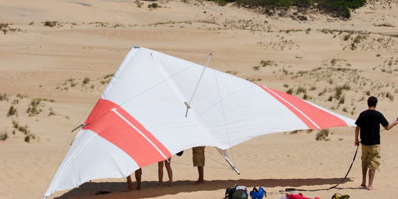 Hang Gliding Red and white hang glider resting on the sand.