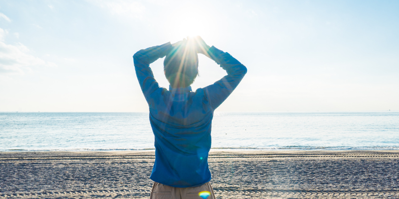 Get Some Sun Sun reflects on person wearing a blue coat to the beach.