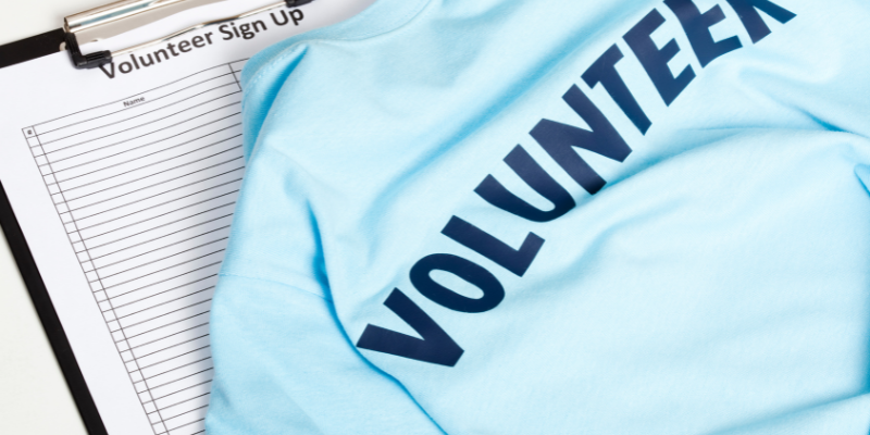 Tips for Voluntourism Blue shirt reading "Volunteer" in front of signup sheet.