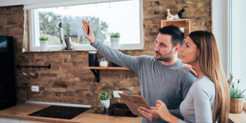 Tips for Theming Your Outer Banks Vacation Rental Man and woman standing in kitchen with arms extended, planning renovations.