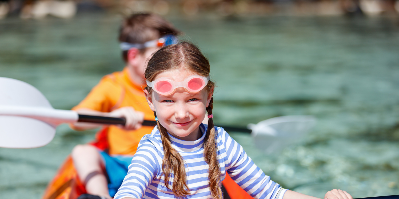 Enjoy a Family Kayaking Adventure! Close up of a girl in a striped shirt kayaking with her brother.