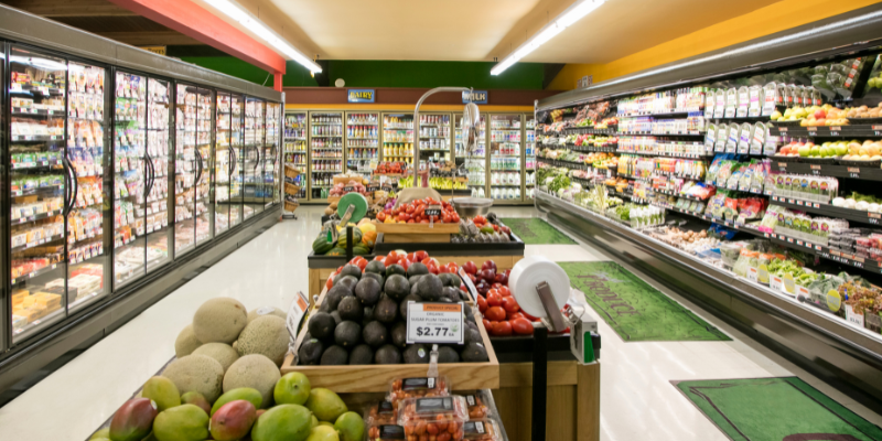 Chain Stores on the OBX Frozen aisle at grocery store with carts of fruits and vegetables.
