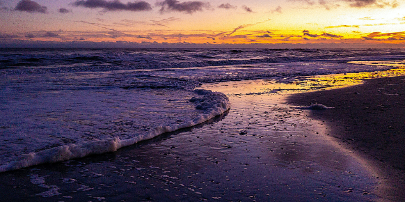 Perks of Visiting the Outer Banks in the Winter Image of high tide, ocean on beach purple sky