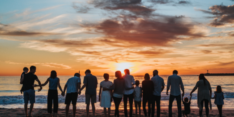 Family on the Outer Banks looking out at the ocean holding hands at sunset.