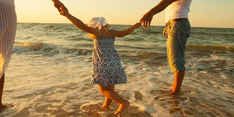 Family at the beach walking through the ocean.