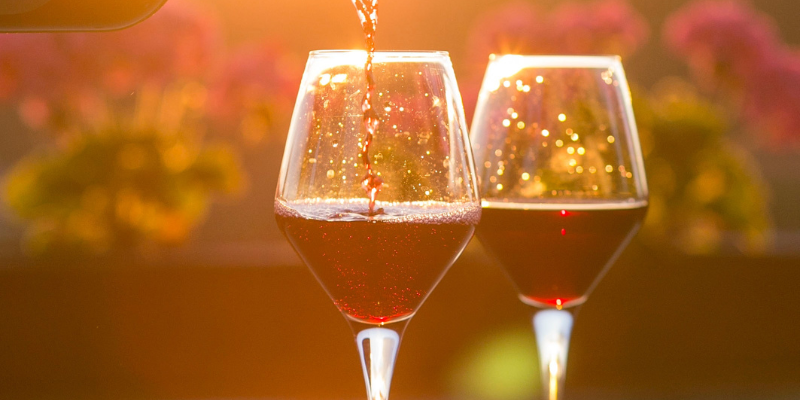 Manteo: Vineyards on the Scuppernong 2 glasses of pink wine against a green and orange sunset background